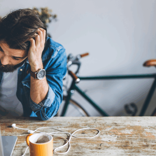 Bearded freelancer at desk with a cup of tea, stressed while preparing business registration paperwork.